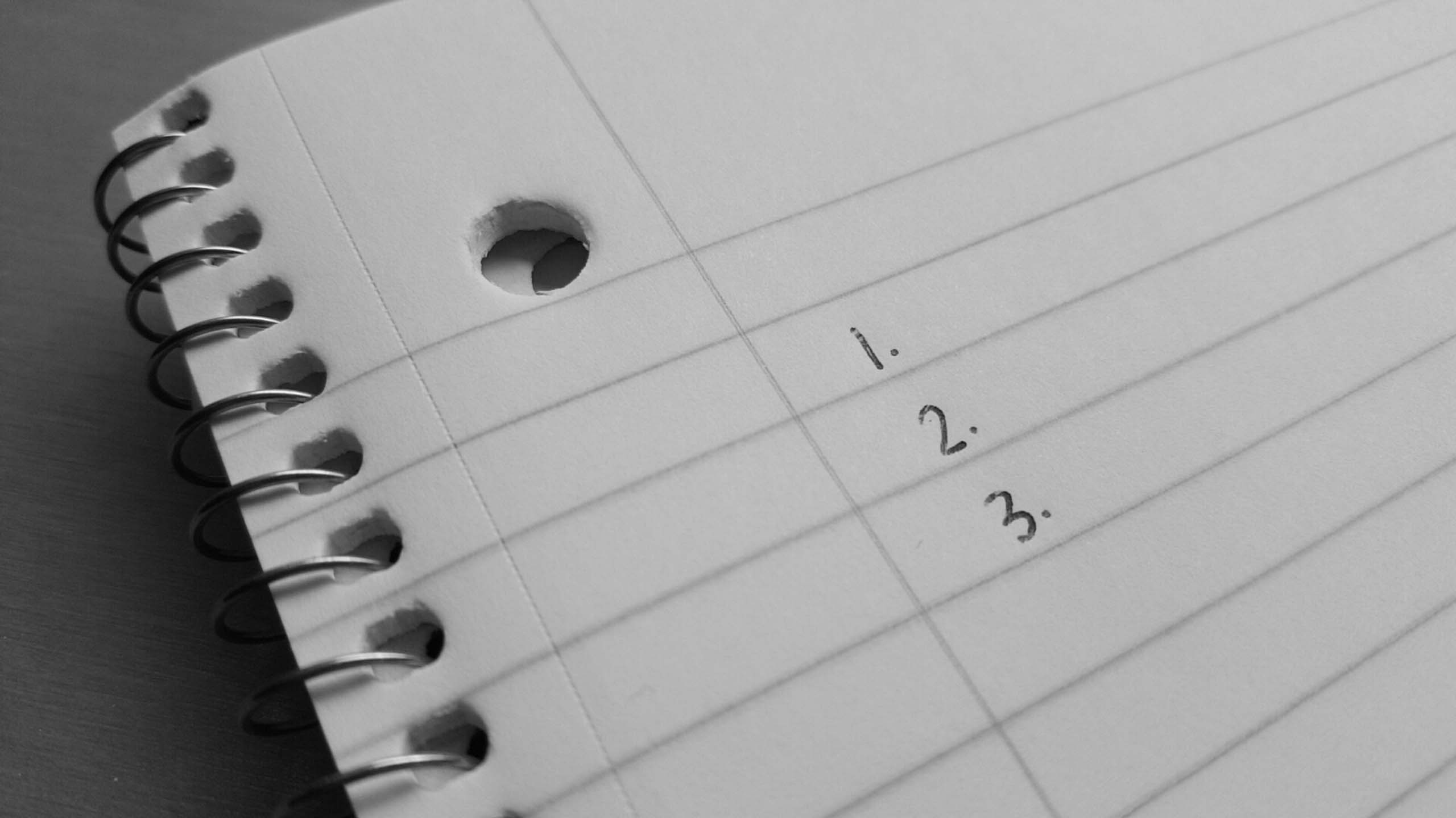 black and white close-up of handwritten steps 1-2-3 on a page of a spiral notebook